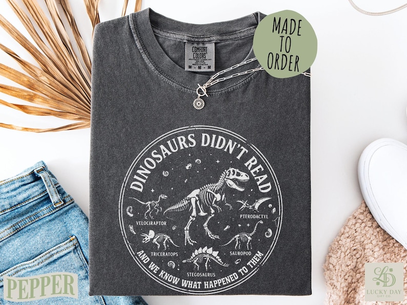 Black t-shirt with "Dinosaurs Didn't Read" text and dinosaur skeletons.