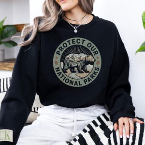 Black crewneck sweatshirt with "Protect Our National Parks" circular graphic featuring a bear.