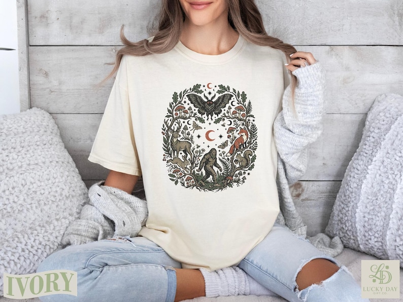 Cream t-shirt featuring a circular woodland creature and plant graphic with a butterfly at the top.
