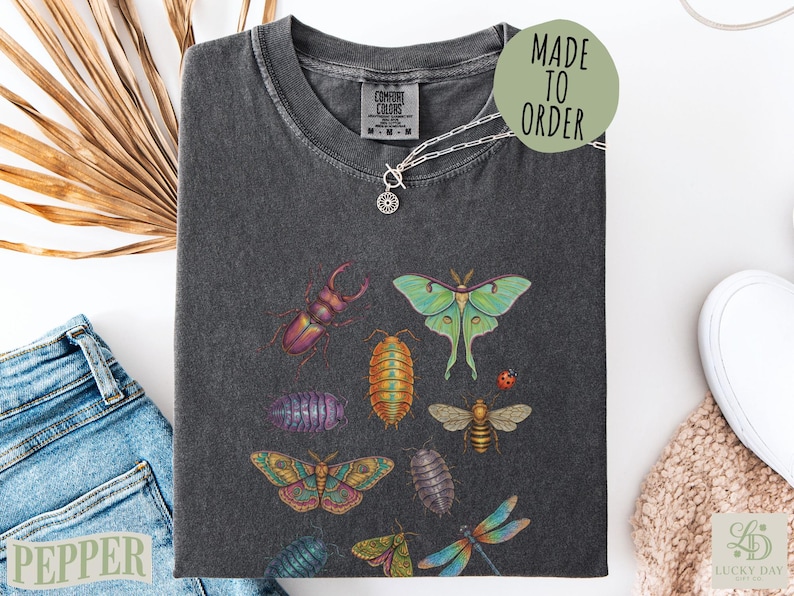 Dark t-shirt with printed insects including moths, beetles, dragonfly, and ladybug.