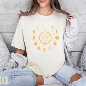 Cream t-shirt with yellow moon phases mandala design, woman wearing shirt.