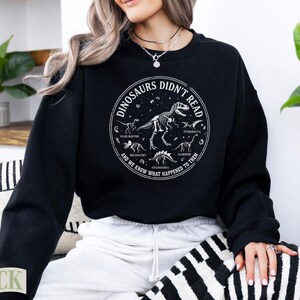 Black sweatshirt with dinosaur skeletons and text "Dinosaurs Didn't Read".
