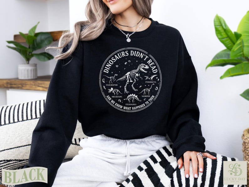 Black sweatshirt with dinosaur skeletons and text "Dinosaurs Didn't Read".