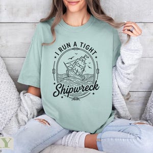 Mint green t-shirt with "I run a tight shipwreck" text and sailing ship graphic.