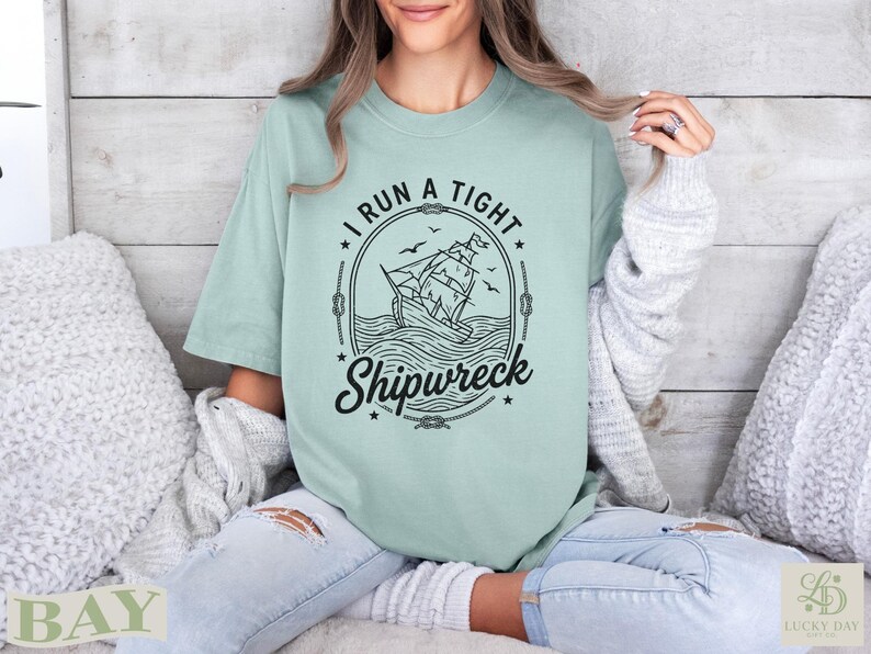 Mint green t-shirt with "I run a tight shipwreck" text and sailing ship graphic.