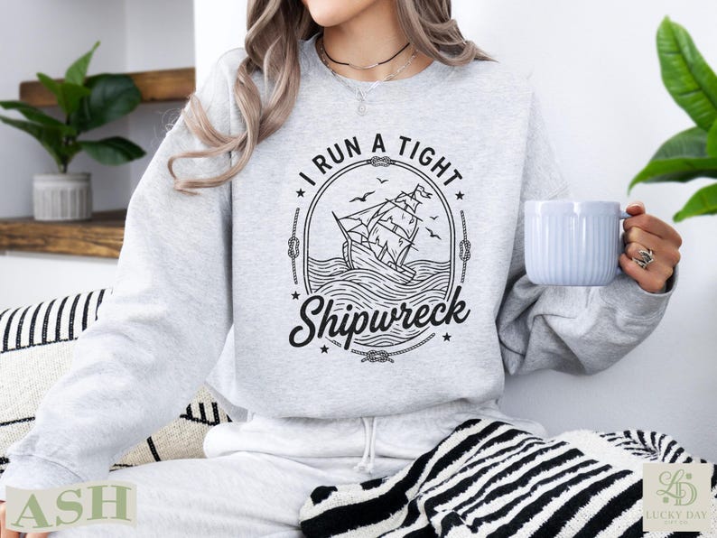Grey sweatshirt with "I RUN A TIGHT Shipwreck" text and sailing ship graphic.
