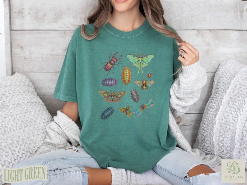 Teal t-shirt with various colorful insects including beetles, moths, and dragonflies.