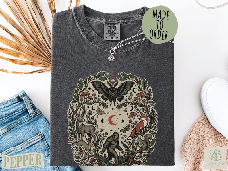 Black t-shirt with mystical forest animal graphic and "Made to Order" text.