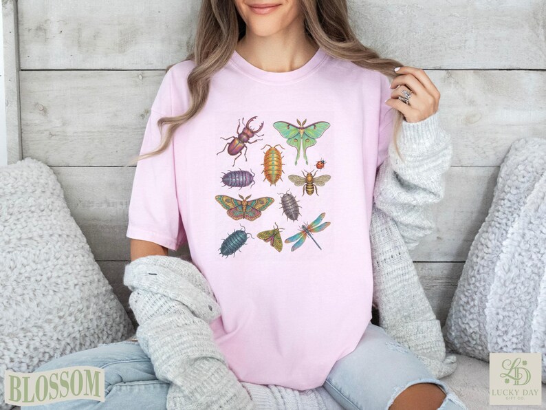 Pink t-shirt with a collage of illustrated insects including butterflies, moths, beetles, and dragonflies.