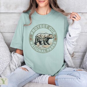 Bear and mountains design on light green t-shirt with "Protect Our National Parks" text.