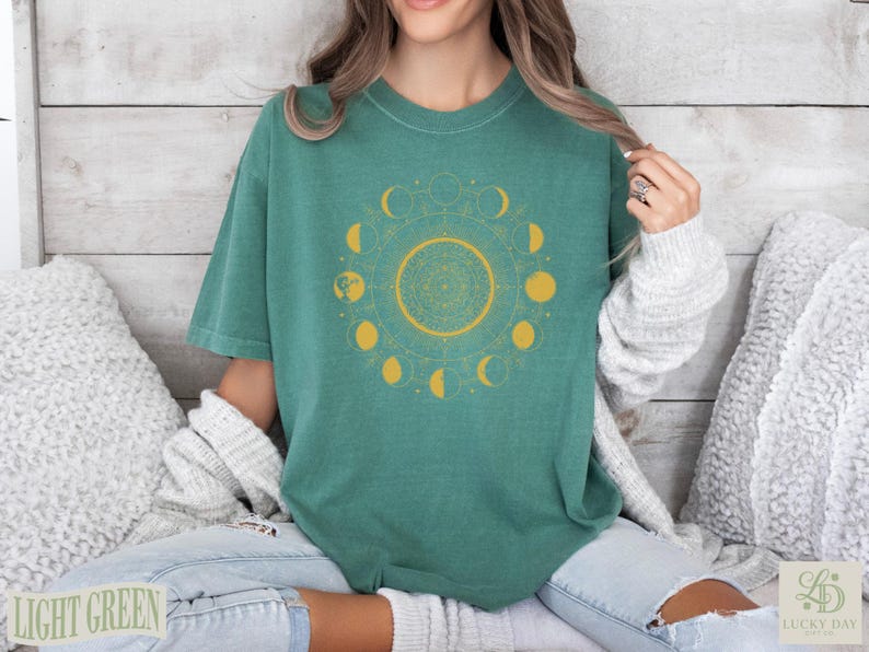 Green t-shirt with gold celestial moon phase mandala design.
