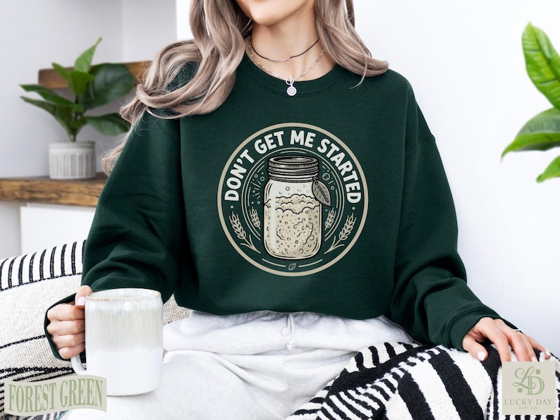 Dark green sweatshirt with "Don't Get Me Started Sourdough" text and mason jar graphic.