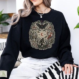 Black crewneck sweatshirt with circular woodland creature and nature design.