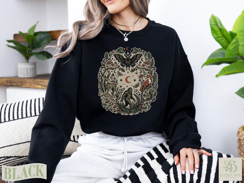 Black crewneck sweatshirt with circular woodland creature and nature design.