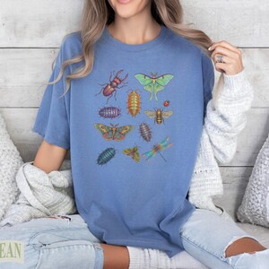 Blue t-shirt with colorful illustrations of insects: beetle, moth, bee, dragonfly.