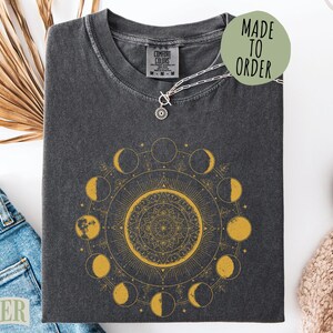 Dark t-shirt with a gold moon phase mandala and "Made to Order" text.