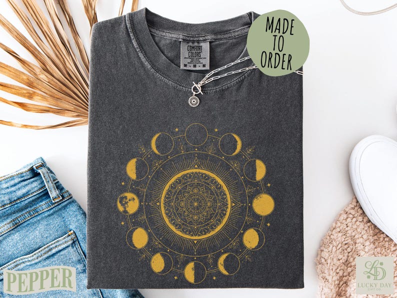 Dark t-shirt with a gold moon phase mandala and "Made to Order" text.