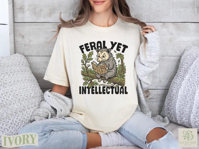 Opossum reading a book titled "Feral Yet Intellectual" on a branch.