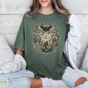 Green t-shirt featuring a circular woodland creature and nature illustration.