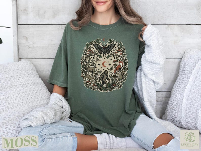 Green t-shirt featuring a circular woodland creature and nature illustration.