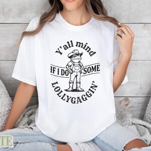 White t-shirt with "Y'all mind if I do some lollygaggin'" and cartoon figure.