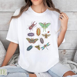White t-shirt with colorful insect illustrations including beetles, moths, and dragonflies.