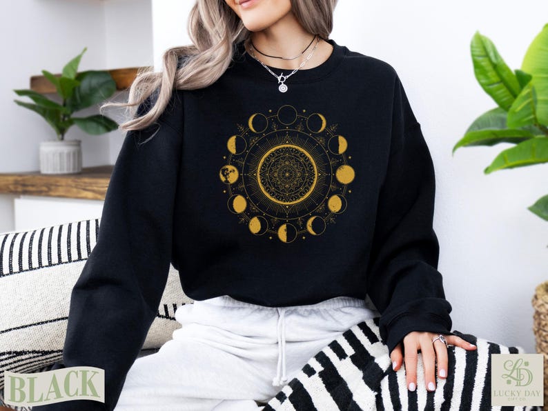 Black sweatshirt with golden celestial moon phases mandala design.