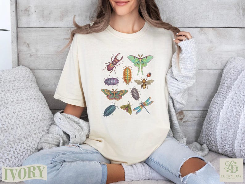 Cream t-shirt featuring an artistic arrangement of various colorful insects.