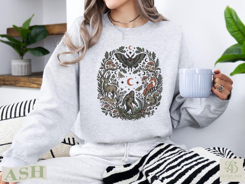 Light grey sweatshirt with woodland creatures and celestial elements design.