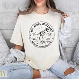 Cream t-shirt with dinosaur skeleton graphic and text.
