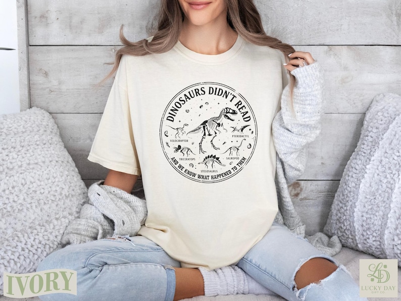 Cream t-shirt with dinosaur skeleton graphic and text.