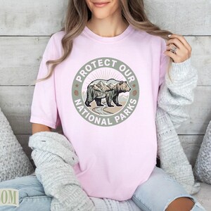 Pink t-shirt with circular "Protect Our National Parks" graphic featuring a bear and mountains.