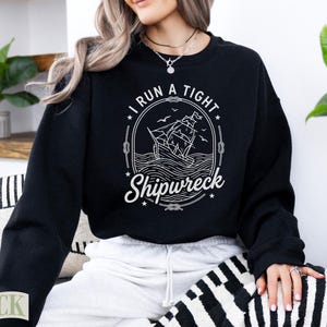Black crewneck sweatshirt with "I Run A Tight Shipwreck" graphic.