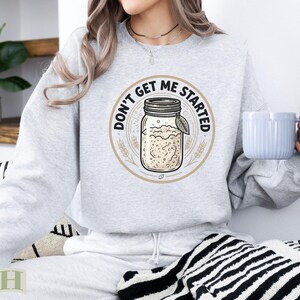 Light grey sweatshirt with "Don't Get Me Started" text and a jar graphic.