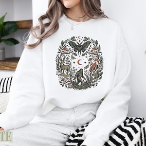 White crewneck sweatshirt with a forest creature design.