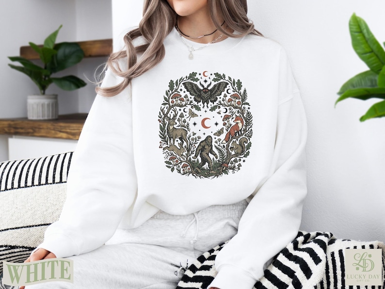 White crewneck sweatshirt with a forest creature design.