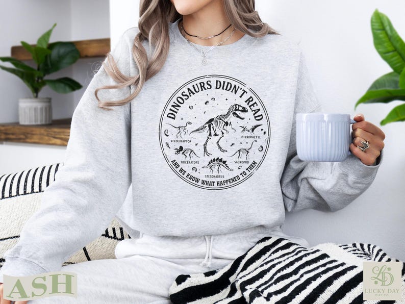 Light gray sweatshirt with dinosaur skeletons and text "Dinosaurs Didn't Read".