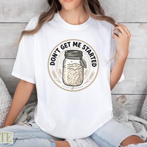 White t-shirt with circular graphic of a jar of starter and the text "Don't Get Me Started".