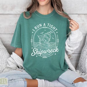 Green t-shirt with "I Run a Tight Shipwreck" and sailing ship graphic.
