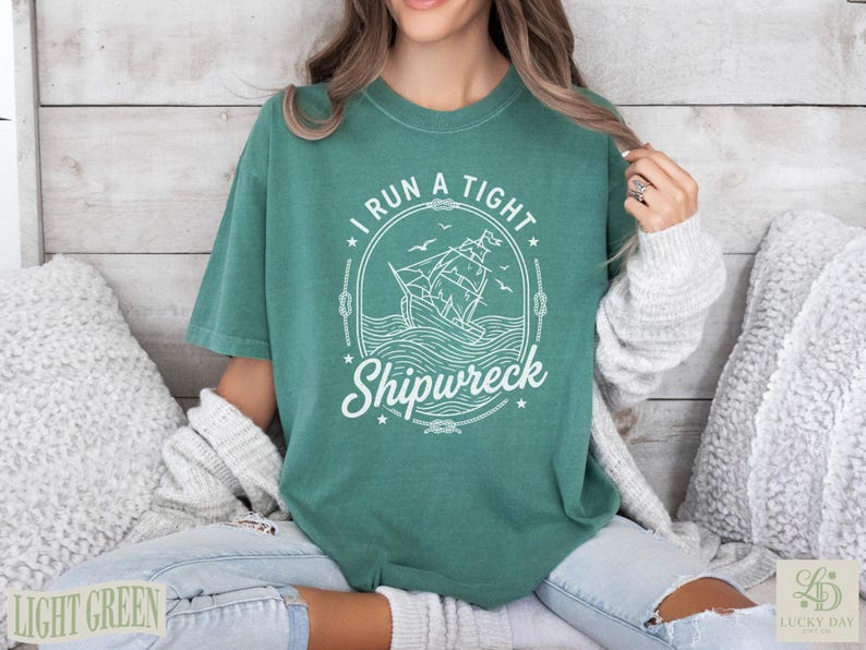 Green t-shirt with "I Run a Tight Shipwreck" and sailing ship graphic.