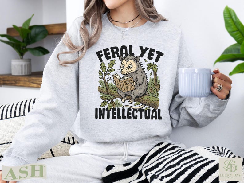 Feral Yet Intellectual sweatshirt with opossum reading book on branch.