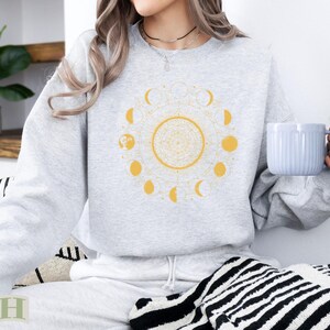 Gray sweatshirt with a yellow sun and moon phase design.