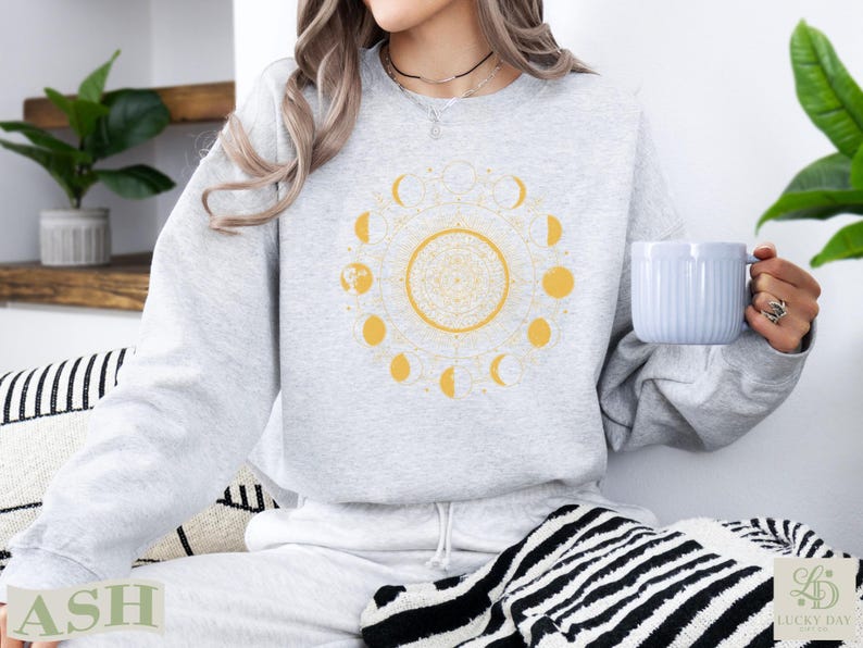 Gray sweatshirt with a yellow sun and moon phase design.