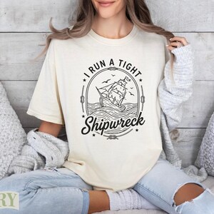 Cream t-shirt with "I run a tight Shipwreck" text and ship illustration.