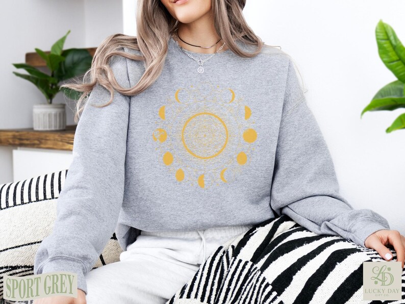Grey sweatshirt with yellow celestial moon phase graphic.