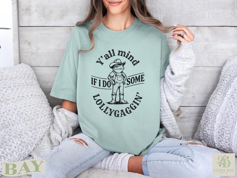 Light green t-shirt with frog illustration and text "Y'all mind if I do some lollygaggin'".
