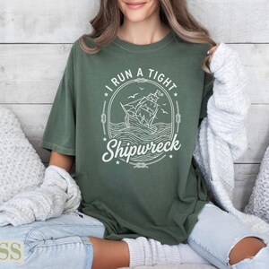 Green t-shirt with a ship and "I RUN A TIGHT SHIPWRECK" graphic.