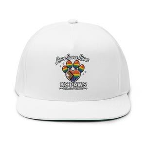 Peut inclure: Casquette blanche à visière plate avec dessous vert. Elle présente un motif de patte colorée avec le texte "Love Saves Lives" et "KC PAWS Dog Rescue Est. 2007". La patte inclut un cœur avec le drapeau sud-africain.