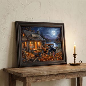 May include: Framed artwork depicting a fall scene with a pumpkin patch, a shop with the text "Jimmy's Road Lakeside Product", and a full moon. A black truck is parked near the shop. A lit candle in a brass holder sits on a wooden table.