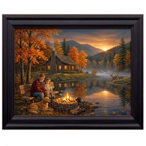 May include: Framed artwork depicting a serene autumn scene. A man and child roast marshmallows by a campfire near a lake, with a golden retriever dog. A cabin sits on the lake's edge, and deer graze nearby. The artwork is framed in a dark brown wooden frame.